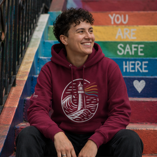 A Beacon Always Burns Hoodie at Pride community stairs marked 'safe here' — queer-owned PNW Pride apparel, front view