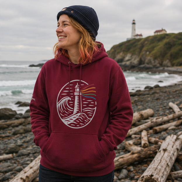 A Beacon Always Burns Hoodie on a Pacific Northwest lighthouse coast — queer-owned PNW Pride apparel, front view