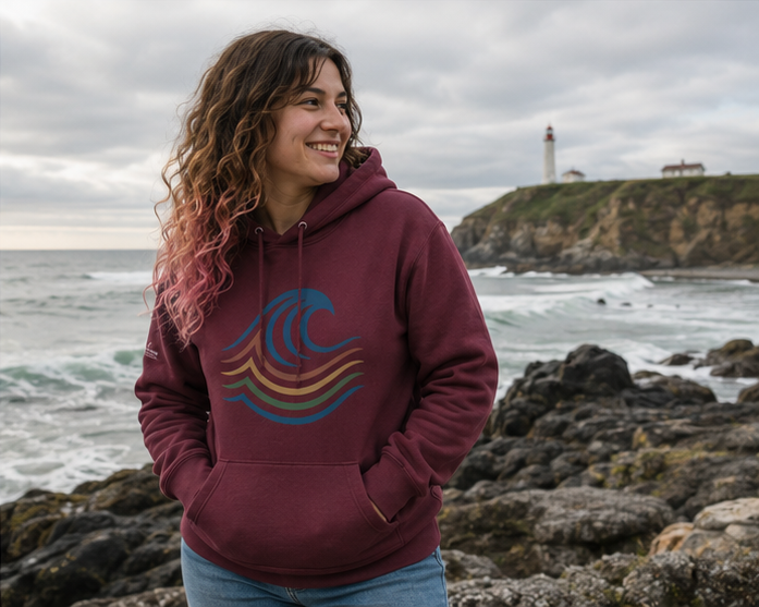 BreakWater Hoodie on a lighthouse on the rocky Pacific Northwest coast — queer-owned PNW Pride apparel, front view