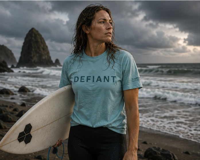 Defiant T-Shirt on a stormy Pacific Northwest coast surf — queer-owned PNW Pride apparel, front view
