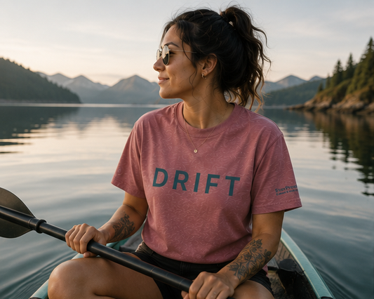 Drift T-Shirt on a Pacific Northwest lake kayak — queer-owned PNW Pride apparel, front view