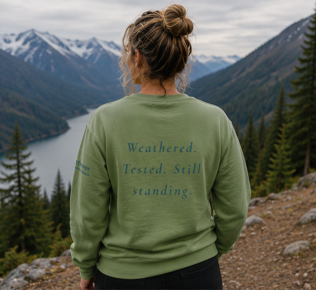 Endure Sweatshirt at a misty Pacific Northwest mountain lake — queer-owned PNW Pride apparel, back view with inspirational quote