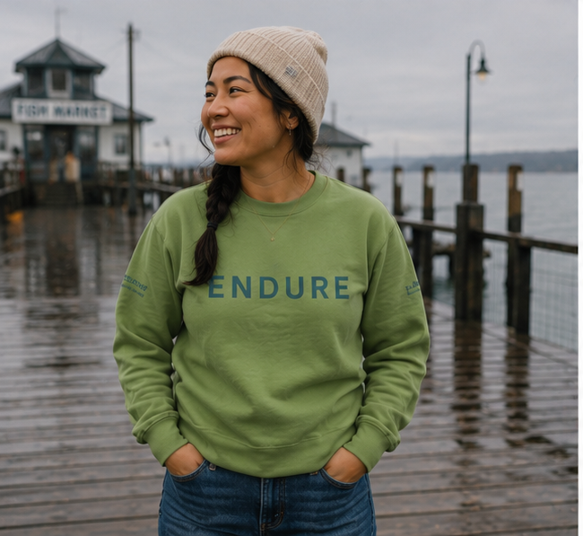 Endure Sweatshirt on a Pacific Northwest waterfront pier — queer-owned PNW Pride apparel, front view