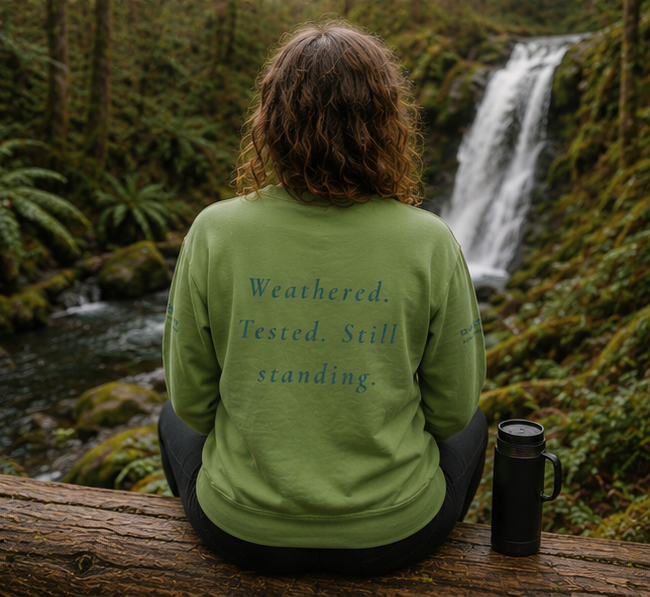 Endure Sweatshirt at a Pacific Northwest forest waterfall — queer-owned PNW Pride apparel, back view with inspirational quote