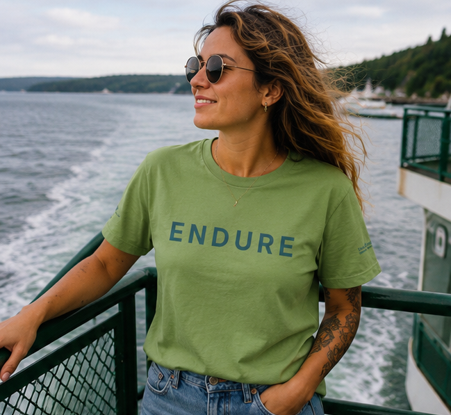 Endure Women's Relaxed T-Shirt at a Pacific Northwest ferry deck — queer-owned PNW Pride apparel, front view
