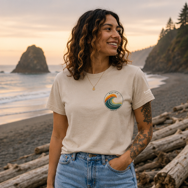 Patchwork Pacific T-Shirt on a Pacific Northwest driftwood beach — queer-owned PNW Pride apparel, front view