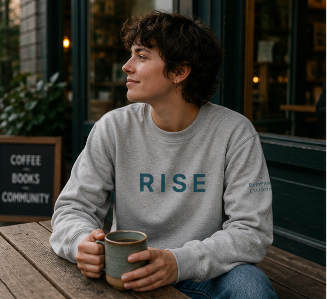 Rise Sweatshirt at a cozy coffee shop with books — queer-owned PNW Pride apparel, front view