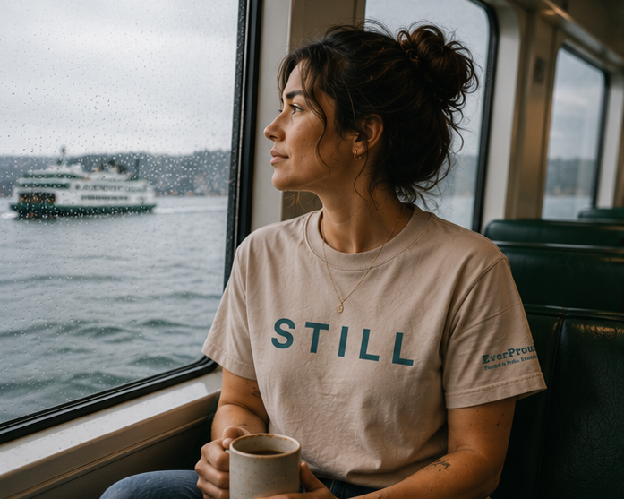 Still T-Shirt at a Pacific Northwest ferry window — queer-owned PNW Pride apparel, front view