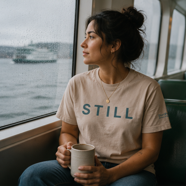 Still Women's Relaxed T-Shirt at a Pacific Northwest ferry window — queer-owned PNW Pride apparel, front view