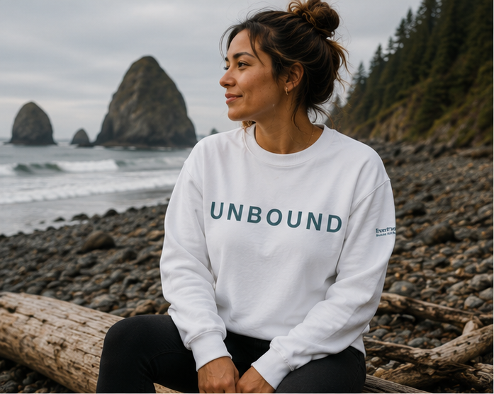Unbound Sweatshirt on the rocky Pacific Northwest coast — queer-owned PNW Pride apparel, front view